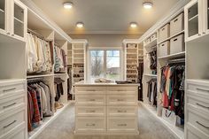 a walk in closet filled with lots of white drawers and shelves next to a window