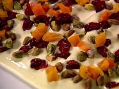 there are many fruits and nuts on top of the cheesecake, which is drizzled with white icing