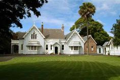 a large white house sitting in the middle of a lush green field with palm trees