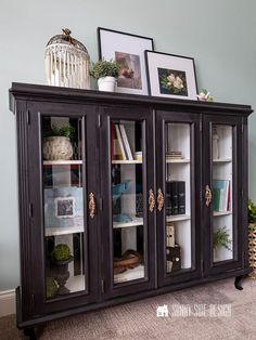 a black cabinet with glass doors and pictures on top