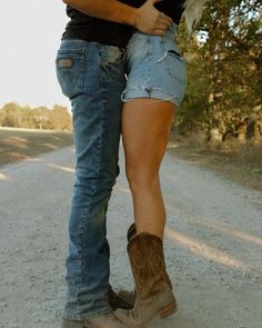 a man and woman standing on the side of a road holding each other's legs