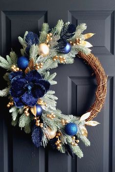 a wreath with blue and gold ornaments hanging on a door