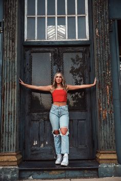 a woman standing in front of a door with her arms spread out and hands behind her head