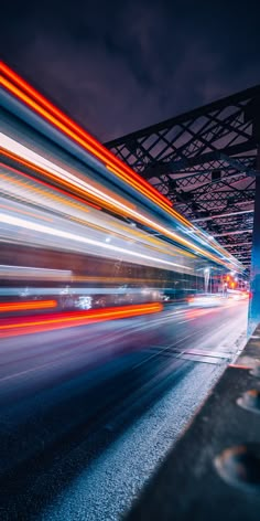 blurry photograph of city street at night with bridge in the backgrouund