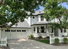 a large white house with trees in front of it and a fence around the driveway