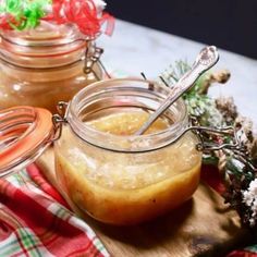 two jars filled with liquid sitting on top of a wooden cutting board next to pine cones