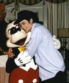 a man hugging mickey mouse on the cheek