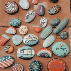 some rocks that have different designs and words on them, sitting on a piece of brown paper