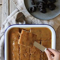 a person is spooning some food out of a casserole dish with raisins on the side