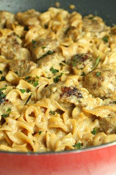 a red pan filled with pasta and meatballs