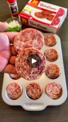 a person holding up some meatballs in a muffin tin with other food items nearby