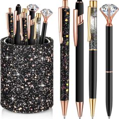 four different types of pens in a cup with glitter and gold trimmings on it