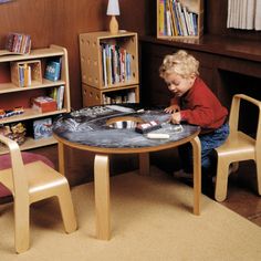 a young child playing with a table and chairs in a room full of bookshelves