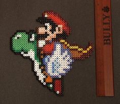 a piece of art made out of perler beads with a ruler next to it