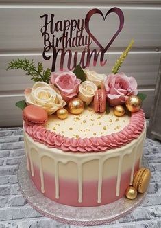 a birthday cake decorated with pink and white frosting, gold decorations and flowers on top