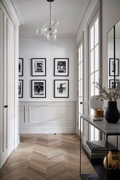 the hallway is decorated with black and white pictures on the wall, along with an elegant vase filled with flowers