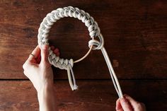 two hands holding a rope on top of a wooden table