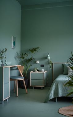 a bedroom with green walls and plants in the corner