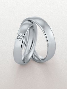 two white gold wedding rings with one diamond on each side and the other in between