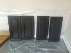 four black doors are sitting on top of a sheeted floor in front of a white wall