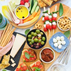 an assortment of food on a wooden platter with cheese, crackers and olives