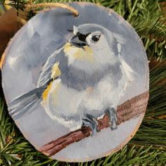 a small bird painted on a wooden ornament hanging from a christmas tree branch