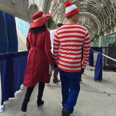 two people in red and white outfits walking down a sidewalk