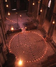 a large circular maze in the middle of a building with candles lit up around it