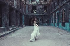 a woman in a white dress walking through an old building