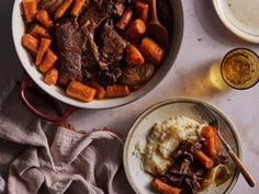 a bowl of meat and carrots next to mashed potatoes with gravy