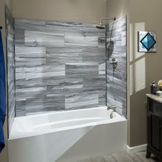 a bathroom with gray and white tiles on the shower wall, bathtub and vanity