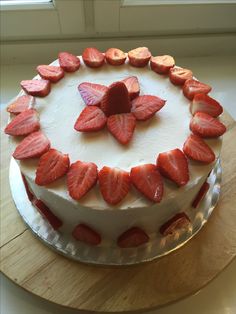 a white cake topped with sliced strawberries on top of a wooden table