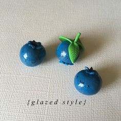 three small blue fruits sitting on top of a table