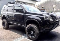 a black truck parked in front of a building with lots of tires and rims