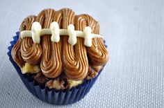 a chocolate cupcake with frosting and football decorations on it's icing