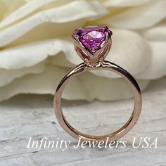 "This ring is a round cut lab created pink sapphire solitaire in 14k rose gold #6465 -Approximate total carat weight: 2.70ctw. diamond equivalent -Center Stone Size: approx. 2.70ct diamond equivalent -Center Stone Shape: round cut / 9 MM -Gem Type: lab created pink sapphire -Stone Clarity: VS2 -Stone Color: Medium Pink -Moh's Scale: 9 hardness -Metal Type and Purity: 14k rose gold -Setting: classic Tulip 4 Prong Setting -Stock Ring Size: 6 -Country of Manufacturing: USA (Michigan) For customizat Pink Brilliant Cut Sapphire Ring In Fine Jewelry Style, Pink Brilliant Cut Sapphire Ring Fine Jewelry, Classic Pink Ruby Ring With Accent Stones, Anniversary Pink Ruby Ring With Center Stone, Pink Brilliant Cut Round Ruby Ring, Pink Brilliant Cut Ruby Ring, Pink Sapphire Promise Ring With Vvs Clarity, Classic Pink Sapphire Ring With Vvs Clarity, Pink Round Cut Ruby Ring In Fine Jewelry Style