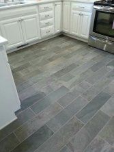 a kitchen with white cabinets and gray tile flooring, stainless steel stove top oven and dishwasher