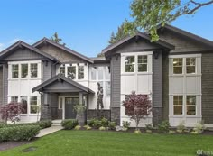 a large house with lots of windows in the front yard and landscaping on the side