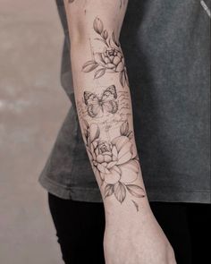 a woman's arm with flowers and butterflies tattooed on the left side of her arm