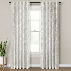 a white curtain hanging on the side of a window next to a potted plant