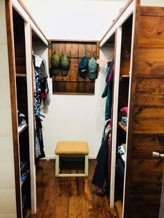 an open closet with clothes hanging on the wall and a small bench in front of it