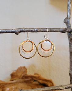 "This is a contemporary geometric earring design. It is made with 3 Semi-precious metals, Sterling, Brass and Copper. These largest ring is Raw Brass, layered with a medium Satin Sterling disc, and finished with a small Raw Copper ring. These three Semiprecious metals create a unique and contemporary earring. 38.00Brass and Copper rings with medium 3/4\" Satin Sterling disc Gift Box Included" Modern White Earrings For Anniversary, Modern White Metal Hoop Earrings, Modern Rose Gold Dangle Earrings, Metal Circle Earrings For Anniversary, Modern Metal Earrings For Anniversary, Nickel Free Rose Gold Circle Earrings, Nickel-free Rose Gold Circle Earrings, Modern Nickel-free Rose Gold Earrings, Anniversary Circle Metal Earrings