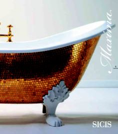 an old fashioned bathtub with gold mosaic tiles on the side and feet, in front of a white wall