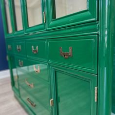 a green dresser with brass handles and drawers