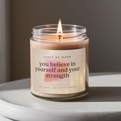 a candle with a quote on it sitting on a table next to a window and the words you believe in yourself and your strength