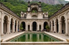 an old building with a pool in the middle and lots of greenery on the side