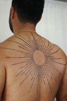 the back of a man's upper body with sunburst tattoo on it