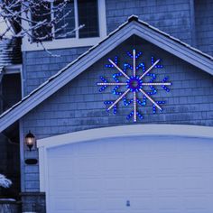 a lighted snowflake on the side of a house in front of a garage