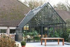 a glass house with a wooden bench in the front yard