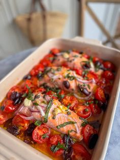 a casserole dish with tomatoes, olives and other vegetables